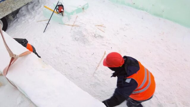 Installers in orange reflective vests and helmets on the installation of ice panels