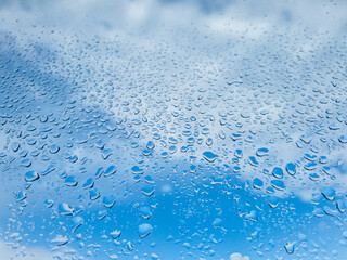 Water drops on a glass under blue cloudy sky