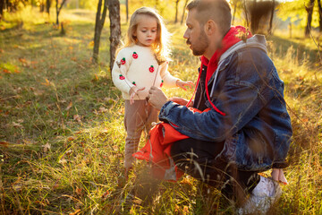 Discover nature. Happy father and little cute daughter walking down the forest path in autumn sunny day. Family time, togehterness, parenting and happy childhood concept. Weekend with sincere emotions