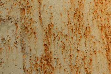 Texture of a light yellow metal plate with peeling paint, splashes and streaks of rust close up