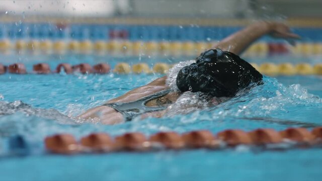 Young female swimmer training front crawl technique for swimming competition. Slow motion shot. 