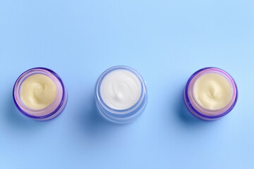 Cosmetic cream in glass jars on color background
