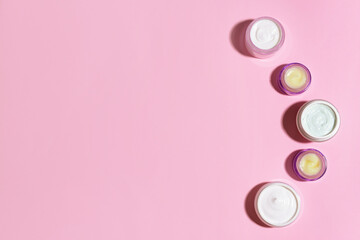 Cosmetic cream jars on color background