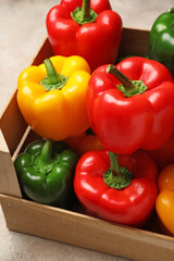 Fresh bell peppers in box on light background
