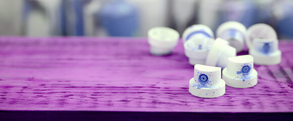 The soiled blue nozzles from the paint sprayer lies on a purple plank on a background of a many...