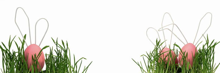 Easter eggs, cute rabbits with white wire ears, peek out from the green grass at the edges of the banner. Easter card, Close-up, white isolated background, selective focus.