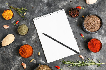 Spices and notebook for recipes on grey background