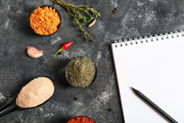 Spices and notebook for recipes on grey background