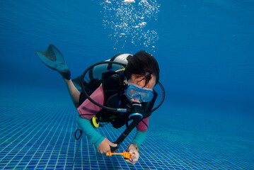 Underwater, a 10 year old boy diving in a pool with fun. This is diving for children.