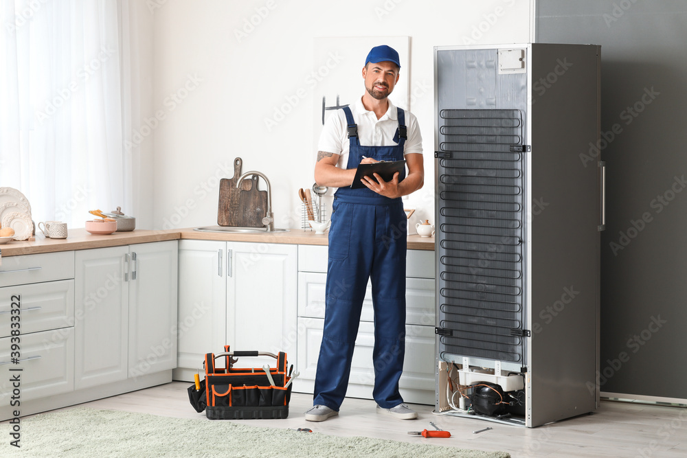 Poster worker repairing fridge in kitchen