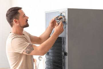 Worker repairing fridge in kitchen