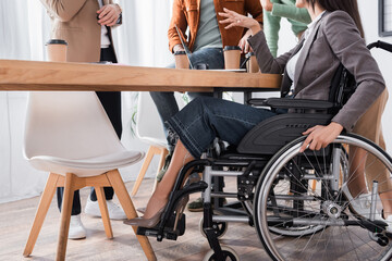 Fototapeta premium cropped view of handicapped businesswoman gesturing during talking with hispanic colleagues
