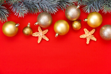 Fototapeta na wymiar Golden Christmas balls decoration and fir branch on a red background with copy space. New Year composition. Flat lay, top view. Minimalistic style.