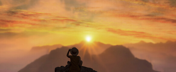 A girl in a hat on top of a hill in silence admires a tranquil landscape in the evening.