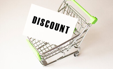 Shopping cart and text DISCOUNT on white paper. Shopping list concept.