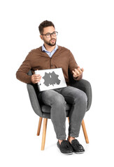 Male psychologist sitting in armchair on white background