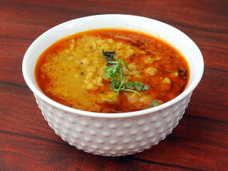 Authentic Indian popular food Dal fry or Traditional Indian soup lentils on rustic wooden background. selective focus