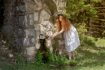 Young woman near the source in the mountains