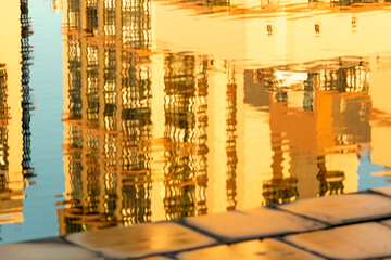 Abstract reflection in the water. Sunny day. Distorted view with ripples. Urban shot. Buildings...