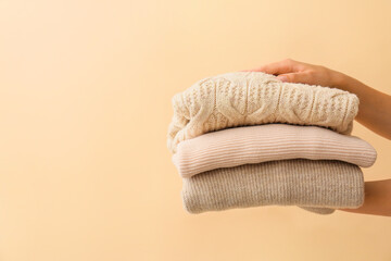 Female hands with warm clothes on color background