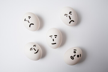 Fototapeta premium Eggs on a white background, with different emotions on their faces