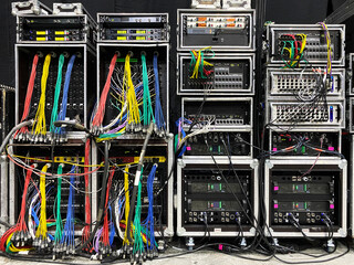 Backstage and tech zone with rack amplifiers, audio signal splitters, patch panels, radio...