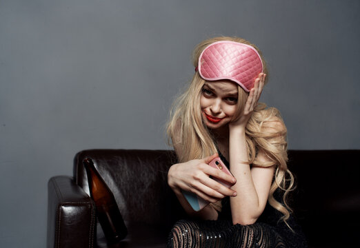 Drunk blonde woman in sleep mask with mobile phone photography model