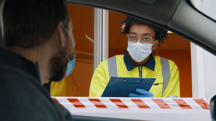 Close up of man driver in mask talking to guard in booth