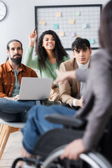 lecturer pointing with finger at smiling hispanic woman raising hand for question