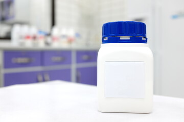 Unlabeled plastic chemical bottle container with cap in a white chemistry laboratory with copy space. 