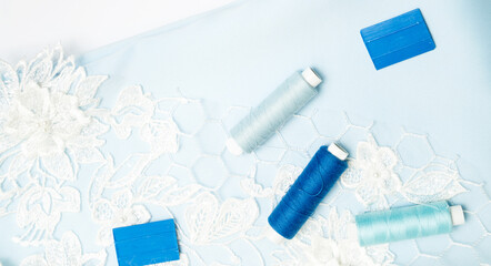 Tailoring concept. beautiful white guipure and blue satin fabric with thread and chalk on a white background. Top view.