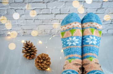 Christmas socks, pine cones and golden bokeh on white bricks background. Person relaxing at home. Winter holiday christmas and new year concept. Copy space
