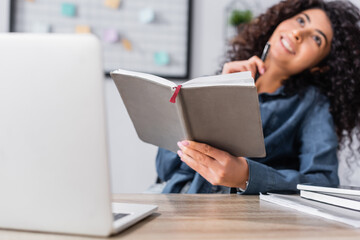 notebook in hand of smiling woman holding notebook on blurred background