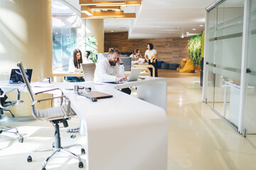 Pensive male worker using laptop in open space office