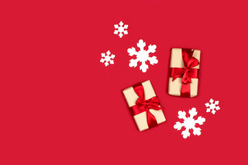 Gifts and white snowflakes flat lay on red background top view, copy space. Creative christmas composition. Christmas shopping. Happy new year, xmas celebration concept. Stock photo