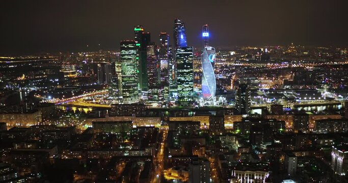 Aerial view of the night city on the background of the luminous towers of Moscow City, Russia