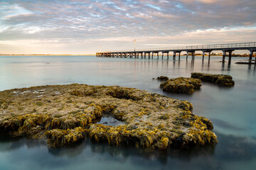 A long exposure  of the coral rock shelfs with the Robe wooden jetty  in the background lcoated in...