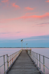 Fototapeta na wymiar A long exposure pastel sunset over the Robe wooden jetty lcoated in Robe South Australia on November 9th 2020