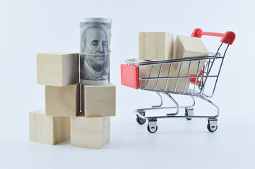 Selective focus of shopping cart, wooden cubes and banknote isolated on a white background. Shopping concept.
