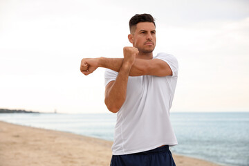 Muscular man doing exercise on beach. Body training