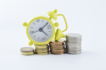 Selective focus of clock and stack of coins isolated on a white background. Time is money concept.