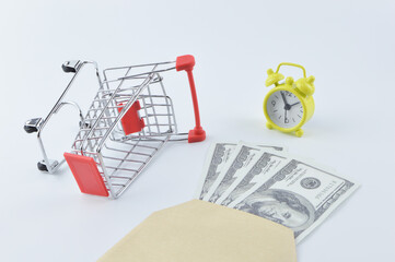 Selective focus of shopping cart, clock, banknotes and envelope isolated on a white background. Shopping concept.