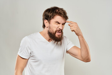 Fototapeta premium bearded man gesturing with his hands in a white t-shirt aggression light background
