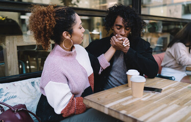 Young multiethnic couple showing affection in cafe
