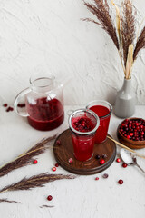 Cranberry juice in glass glasses on a concrete background. Berry cold drink.