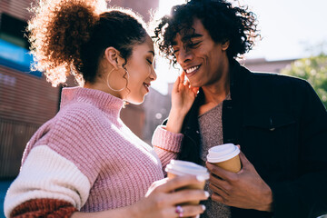 Happy ethnic couple with takeaway beverages during date