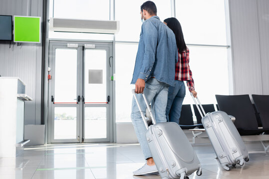 interracial couple walking with luggage in departure lounge