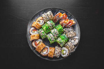 set of sushi roll with salmon, avocado, cream cheese, cucumber, rice, tuna in plate on black background