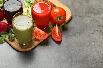 Delicious vegetable juices and fresh ingredients on grey table. Space for text