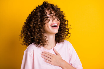 Photo portrait of girl with curly hairstyle wearing t-shirt laughing keeping hand on chest isolated...